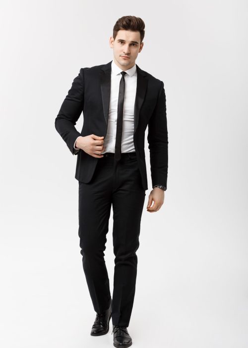 Business Concept: Full length portrait picture of a elegant business man in smart suit walking on white background